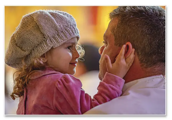 Father holding her daughter as she caresses him.